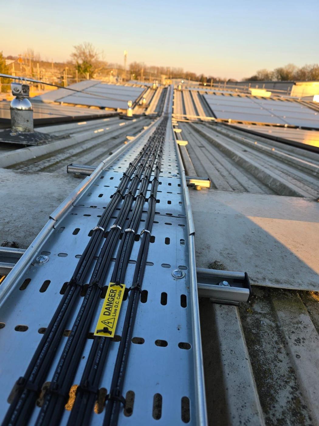 DC cables neatly tied in tray across the roof with danger label