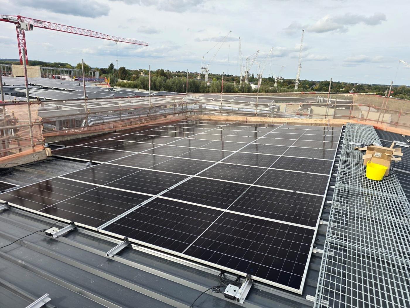 Rows of solar panels on a big commercial roof on a sunny day