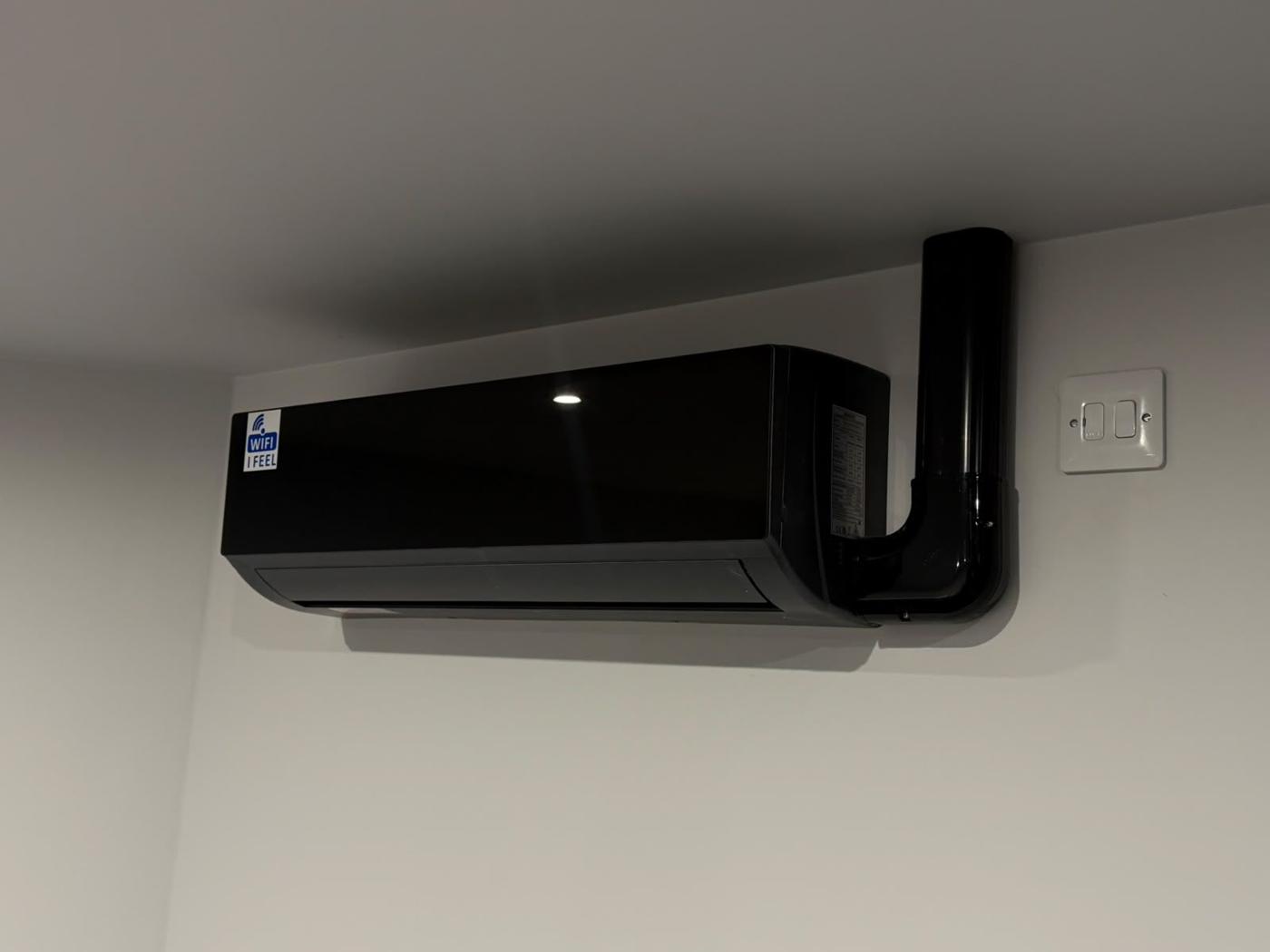 Black split AC indoor unit below a ceiling