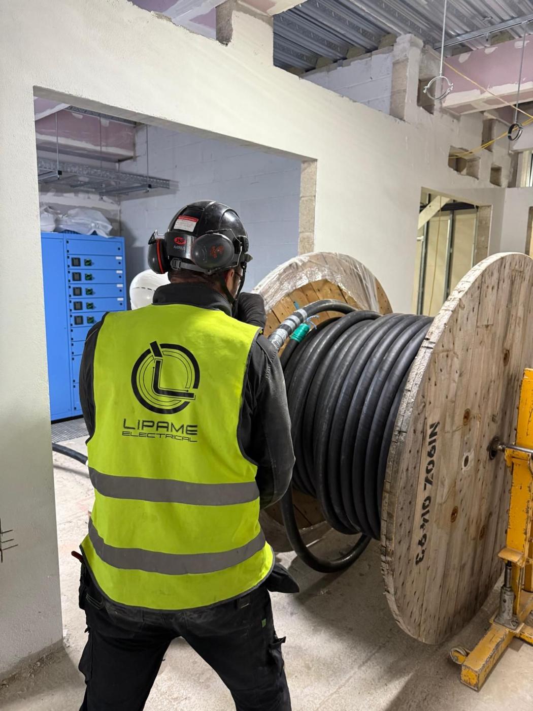 Lipame electrician pulling cable from a drum on site