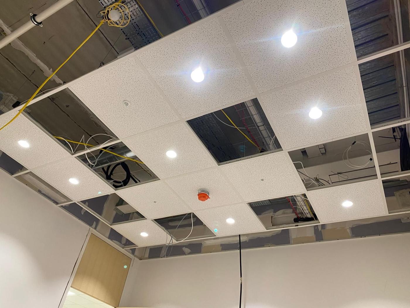 New LED downlights being installed in a suspended ceiling