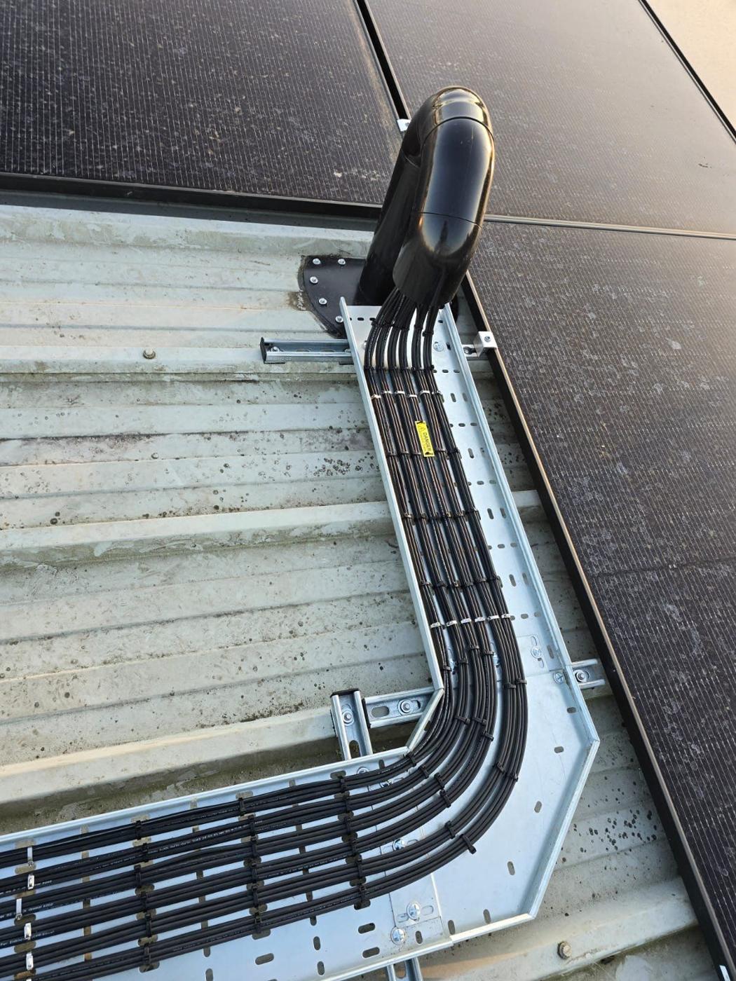 DC cables entering the building through a weatherproof roof entry, laid in tray