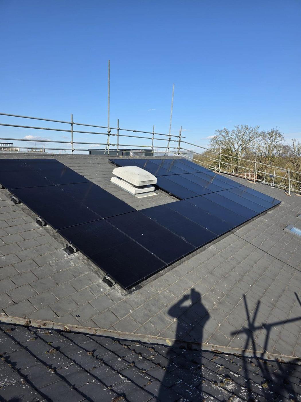 All-black solar panels on a slate roof with scaffold edge protection