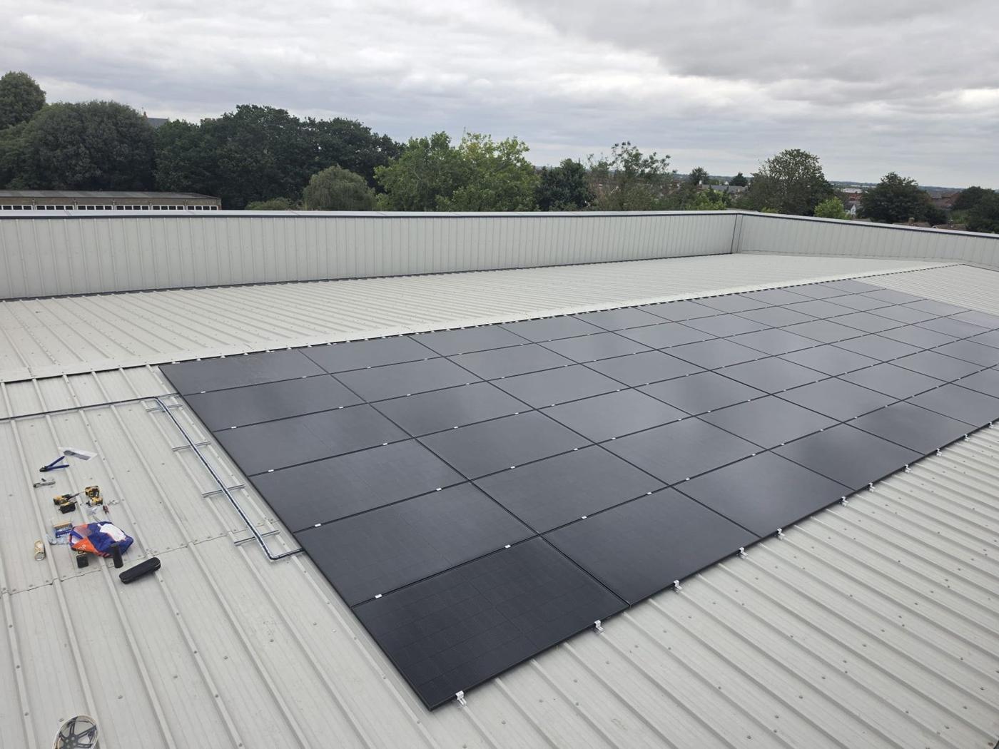 Large rectangular solar array on the metal school roof at Plume Academy
