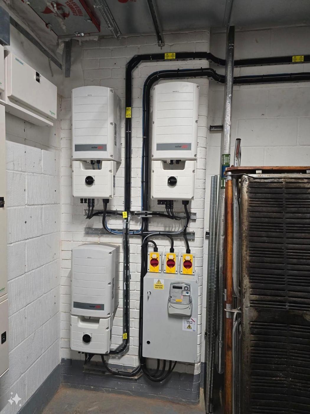 Two inverters, isolators and meter neatly fitted in a plant room