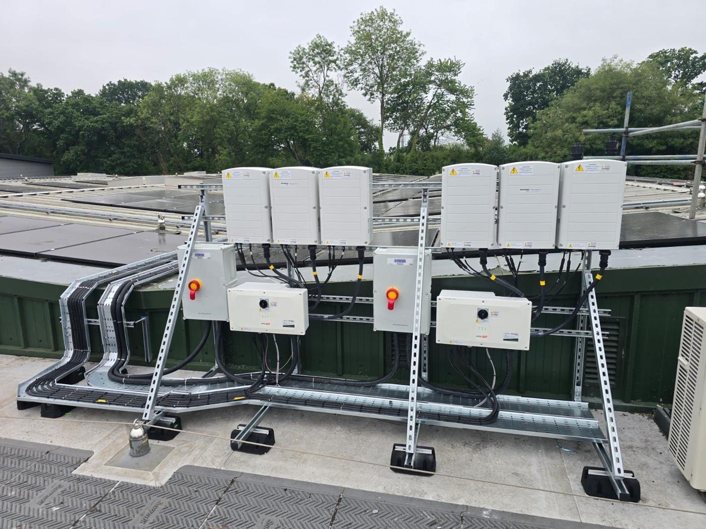 Six inverters with AC isolators on a steel frame on a flat roof in Winchester