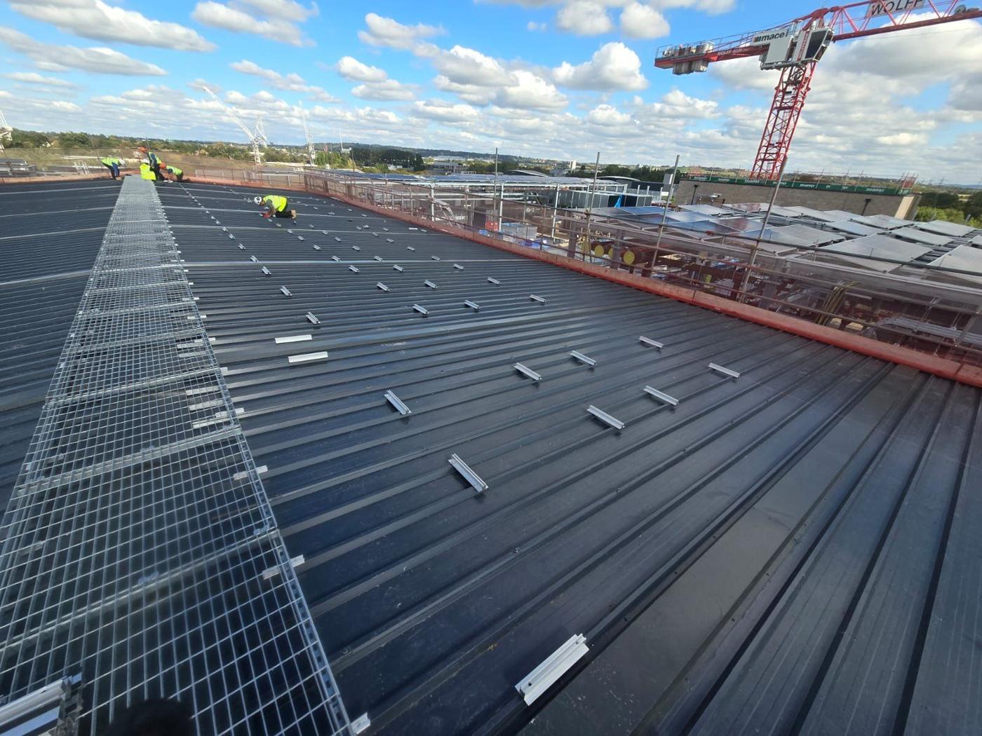 Rails on a big roof with tower cranes behind