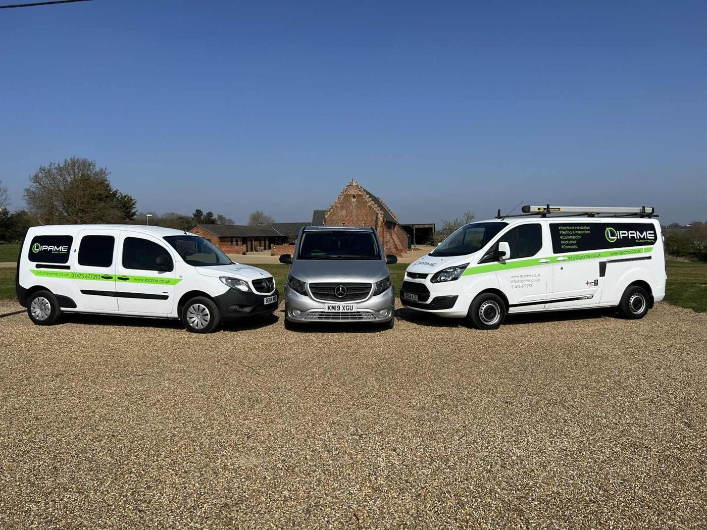 Three Lipame vans lined up in front of a brick barn
