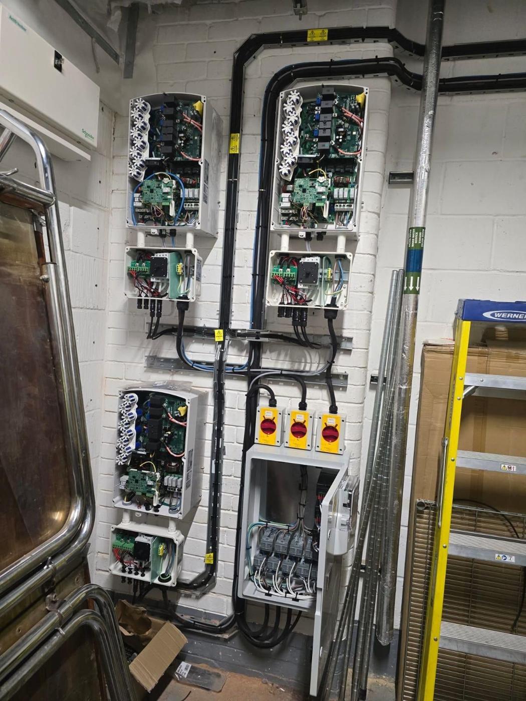 Three commercial inverters with AC isolators in a plant room