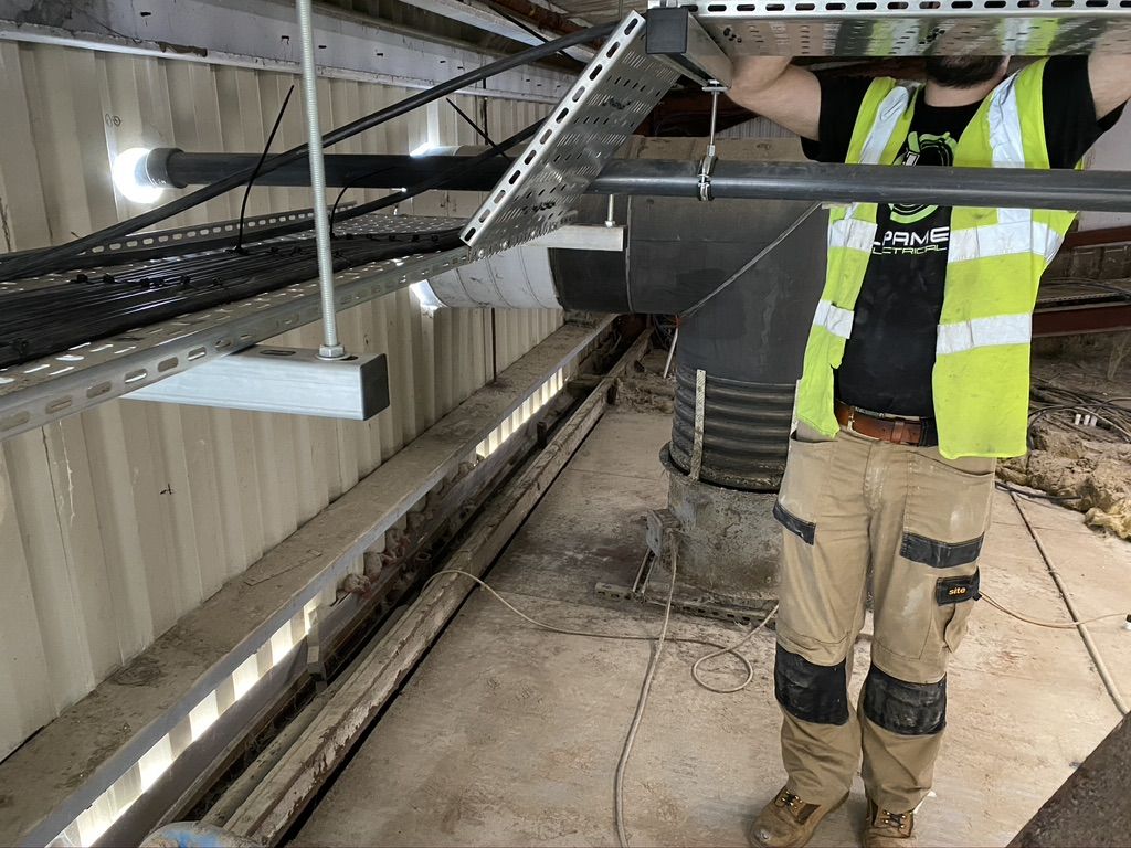 Engineer fitting cables on tray along the factory